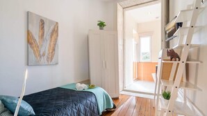 Una camera da letto con un letto, un armadio, una scrivania e una scala.
