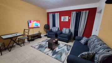 Ein Wohnzimmer mit Sofa, Couchtisch, Fernseher und Ventilator.