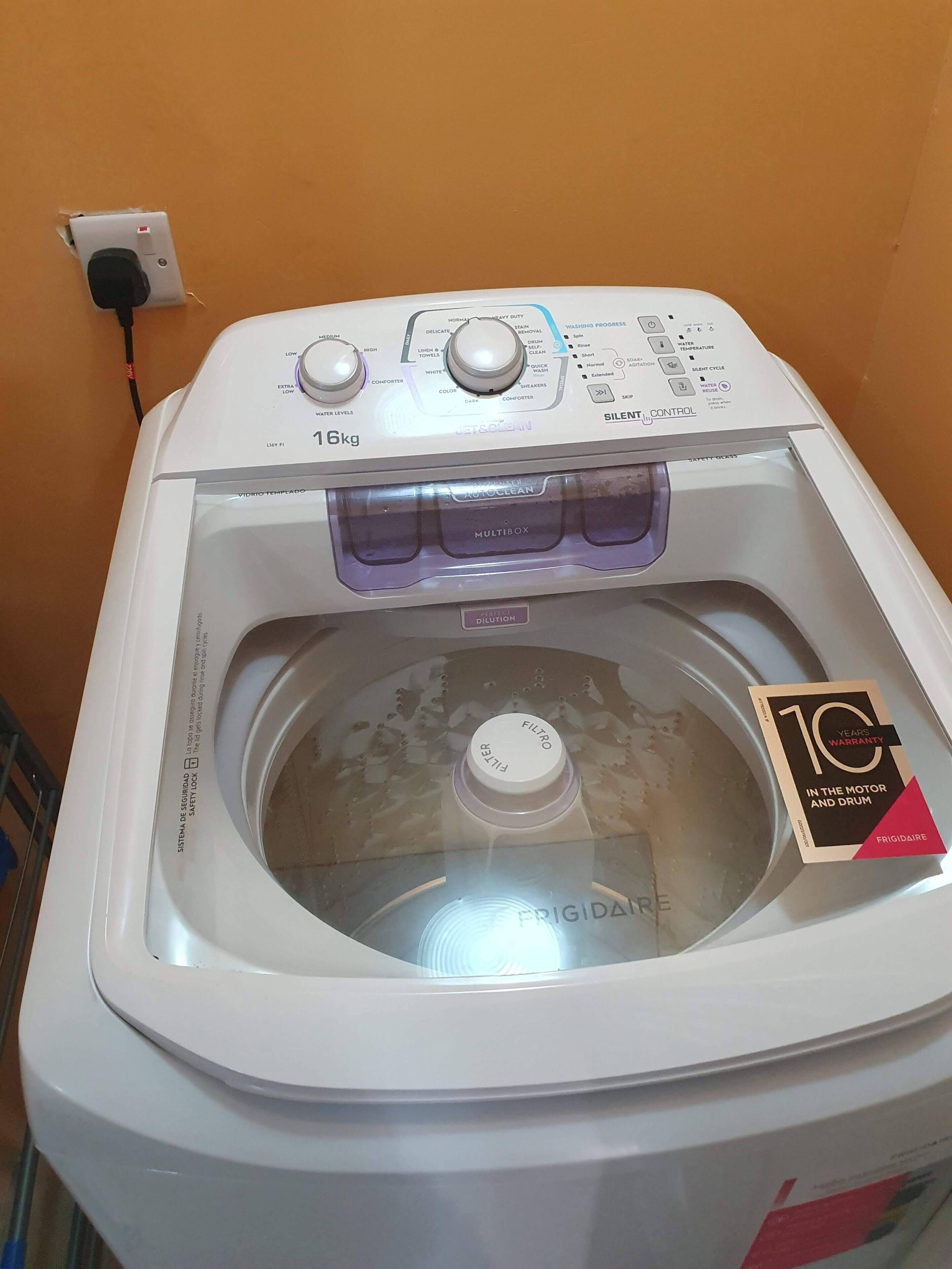 A front view of a washing machine with a control panel, a water level indicator, and a 10-year warranty label.