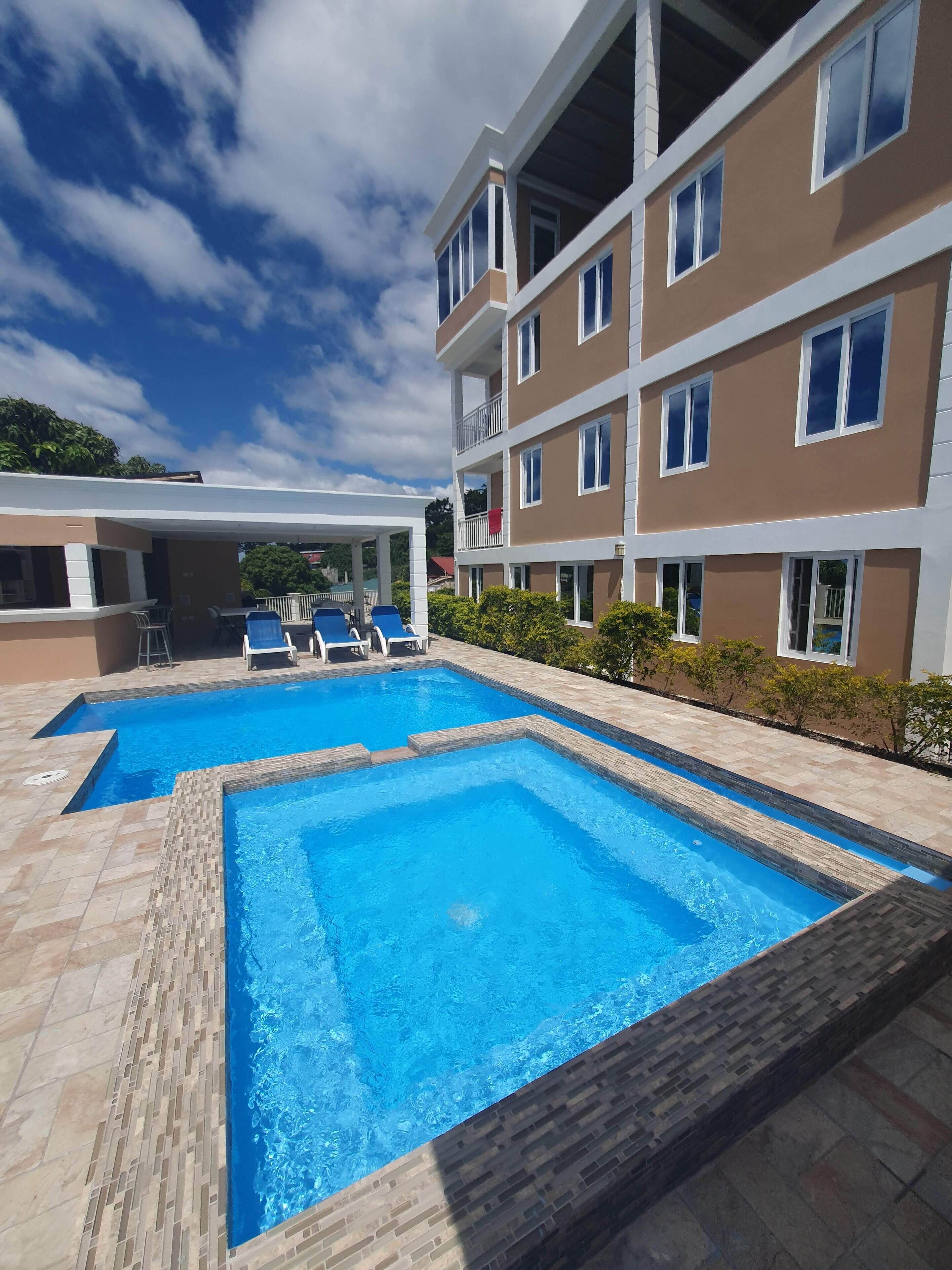 A swimming pool with two separate sections, surrounded by a tiled deck.