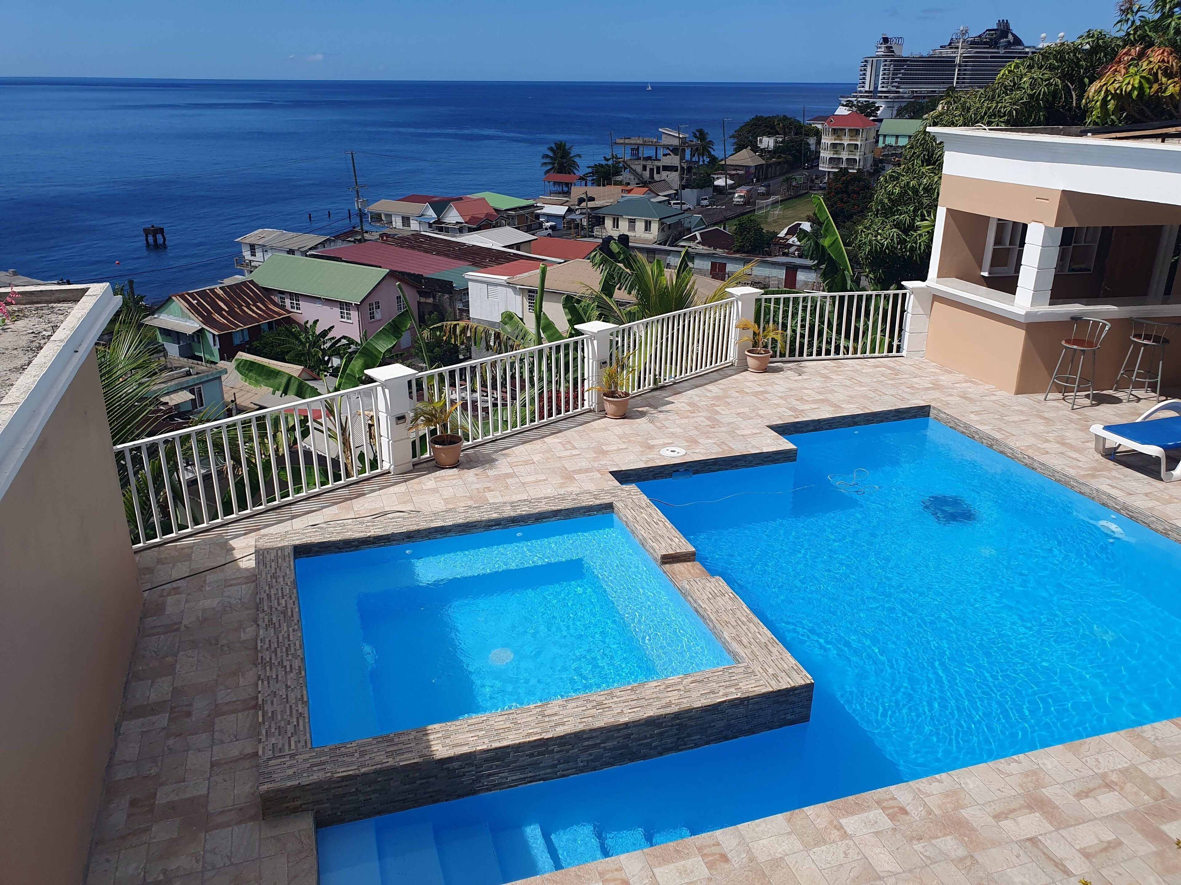 A swimming pool with a view of the ocean and surrounding buildings.