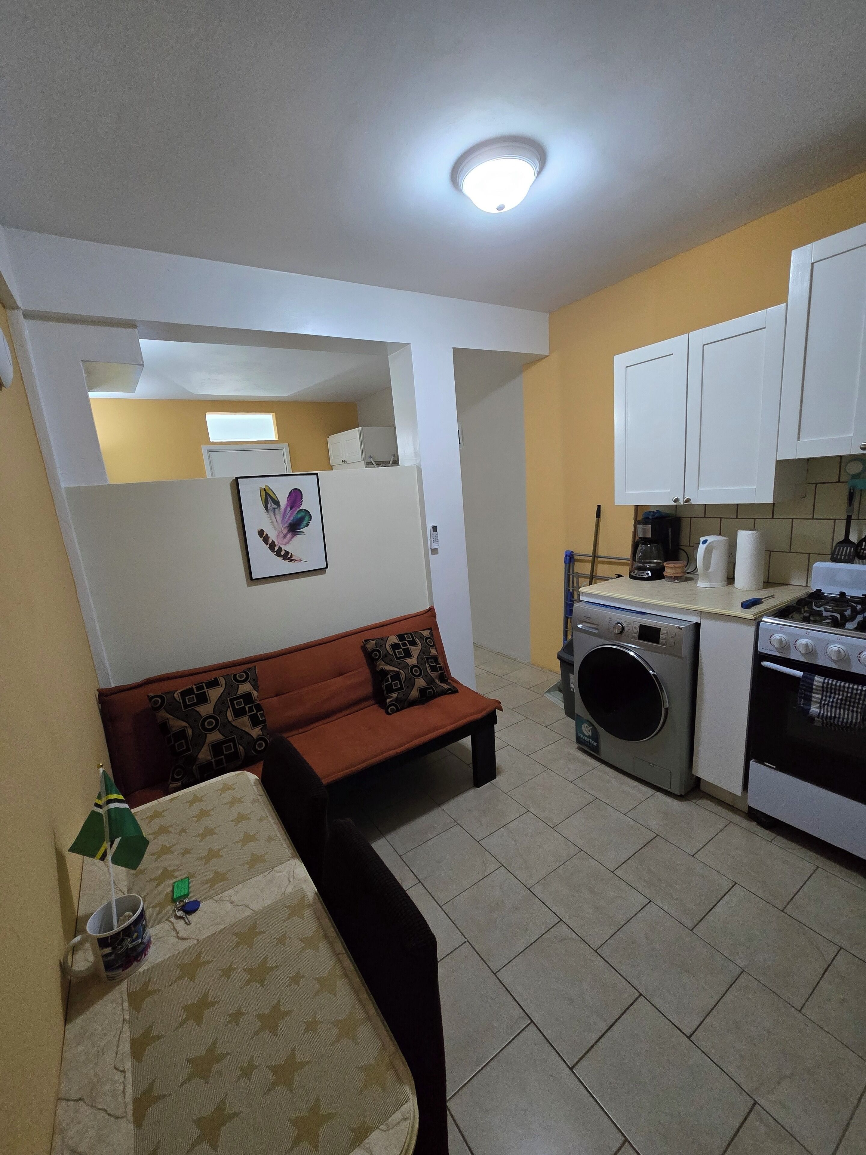 A compact living space with a sofa, a washing machine, and a stove.
