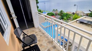 Balkon med havudsigt, pool og en stol.