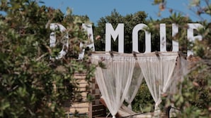 A large outdoor sign with the word "AMOUR" partially obscured by foliage. - Del Mare Beach Hotel (Corfu)
