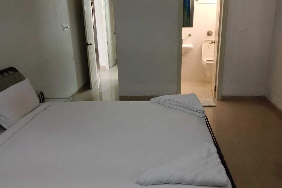A hotel room with a bed, a bathroom visible through an open door, and a tiled floor.
