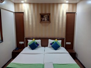 A hotel room with two beds, a painting on the wall, and a telephone on the nightstand. - Serenity By Monarch Viman Nagar (Pune)