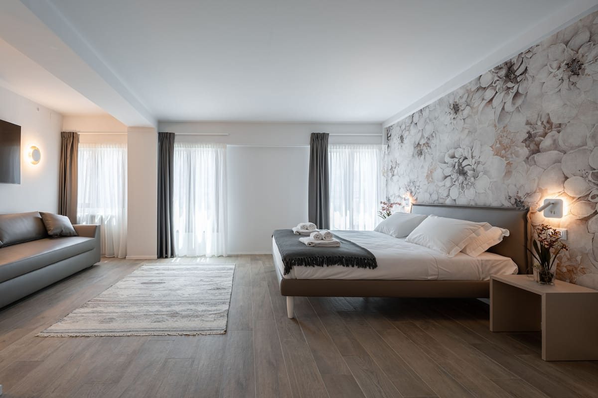 Une chambre moderne comprenant un lit, un canapé, une table de chevet et un luminaire fixé au mur.