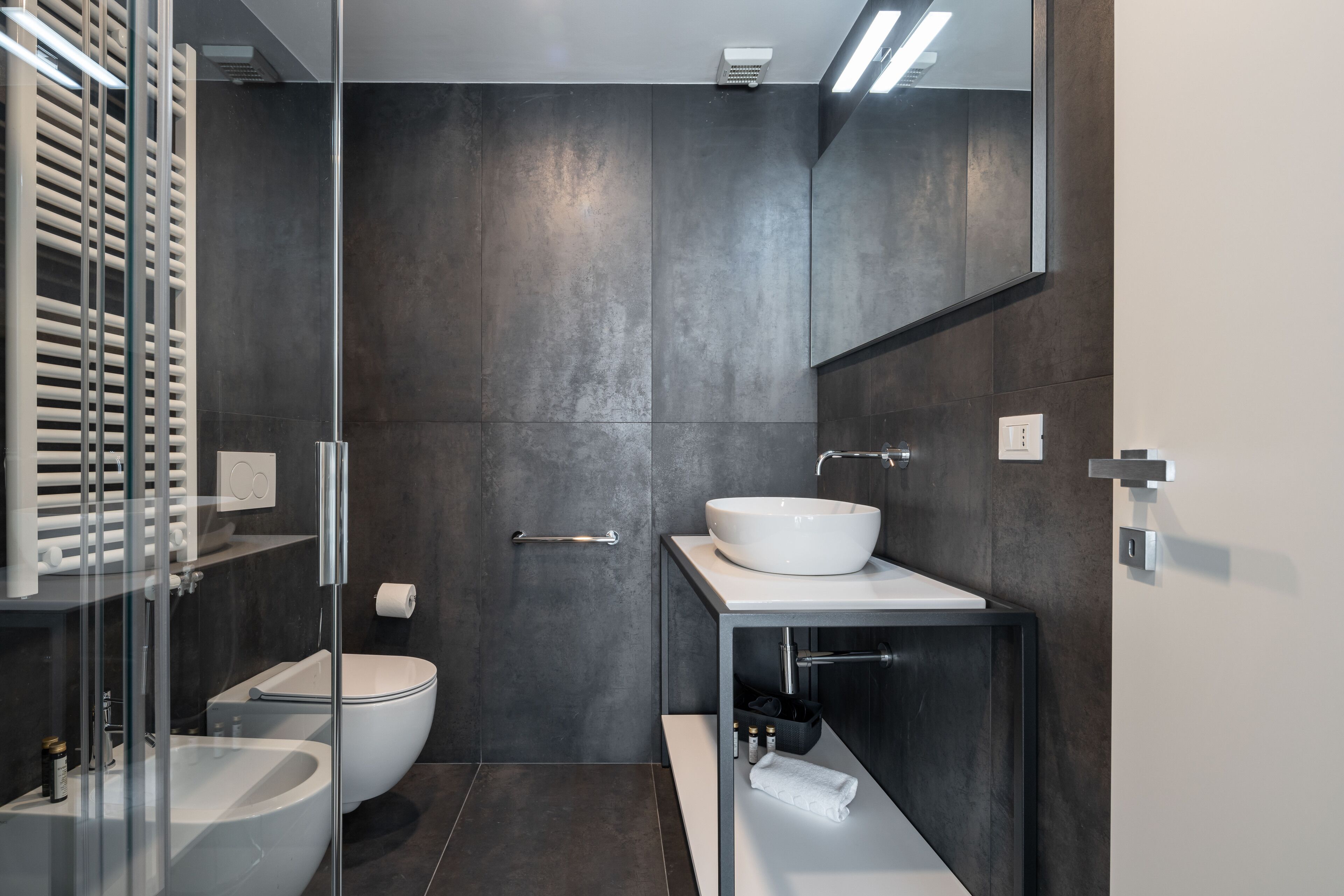 Une salle de bain moderne avec une douche à l’italienne en verre, un lavabo blanc et des toilettes.