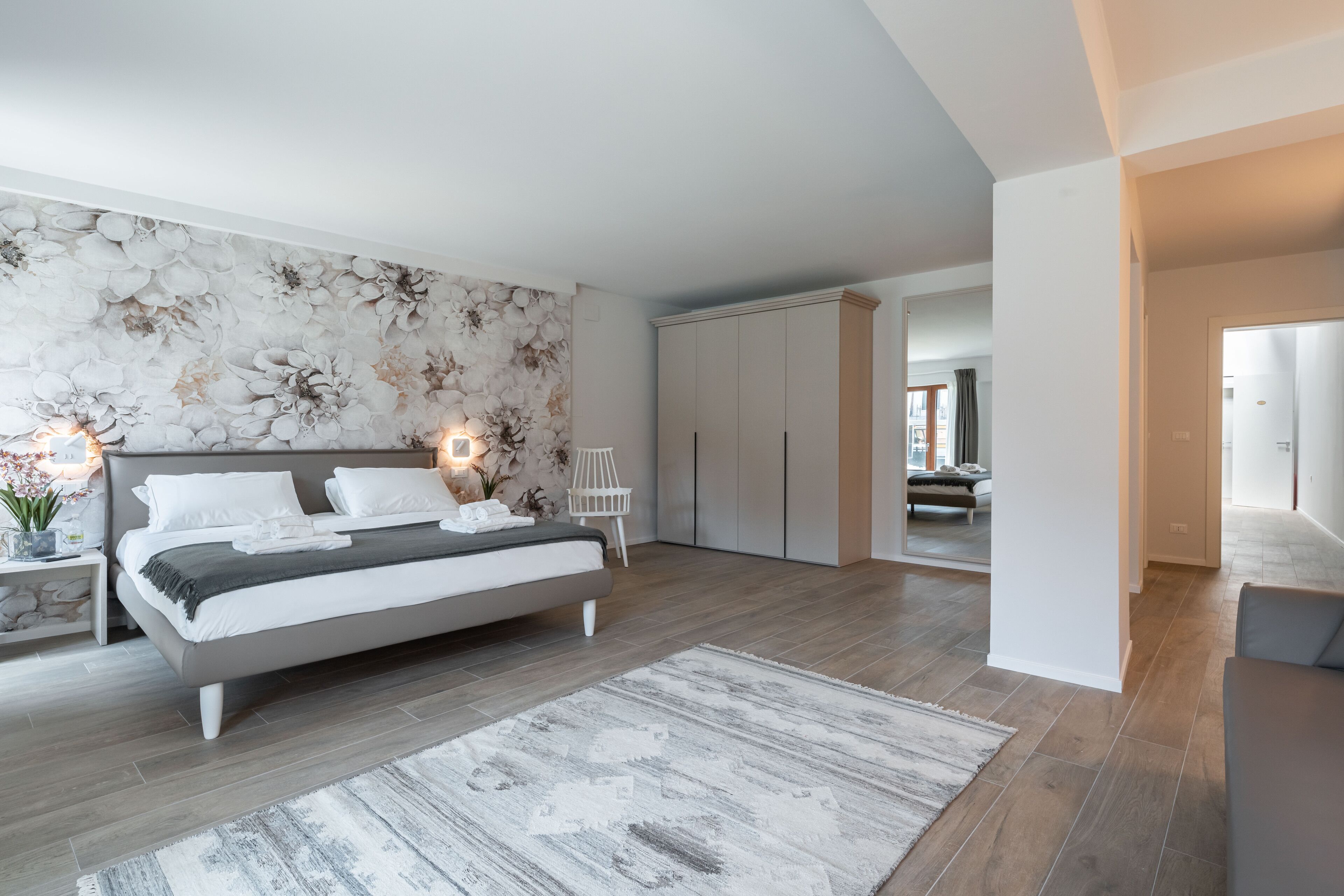 A modern bedroom with a large bed, a decorative wall, and a wardrobe.