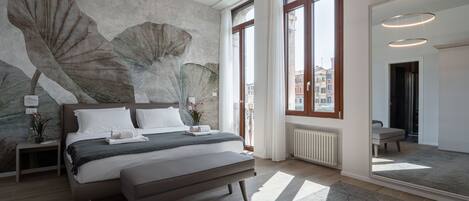 A modern bedroom with a large bed, a wall mural, and large windows.