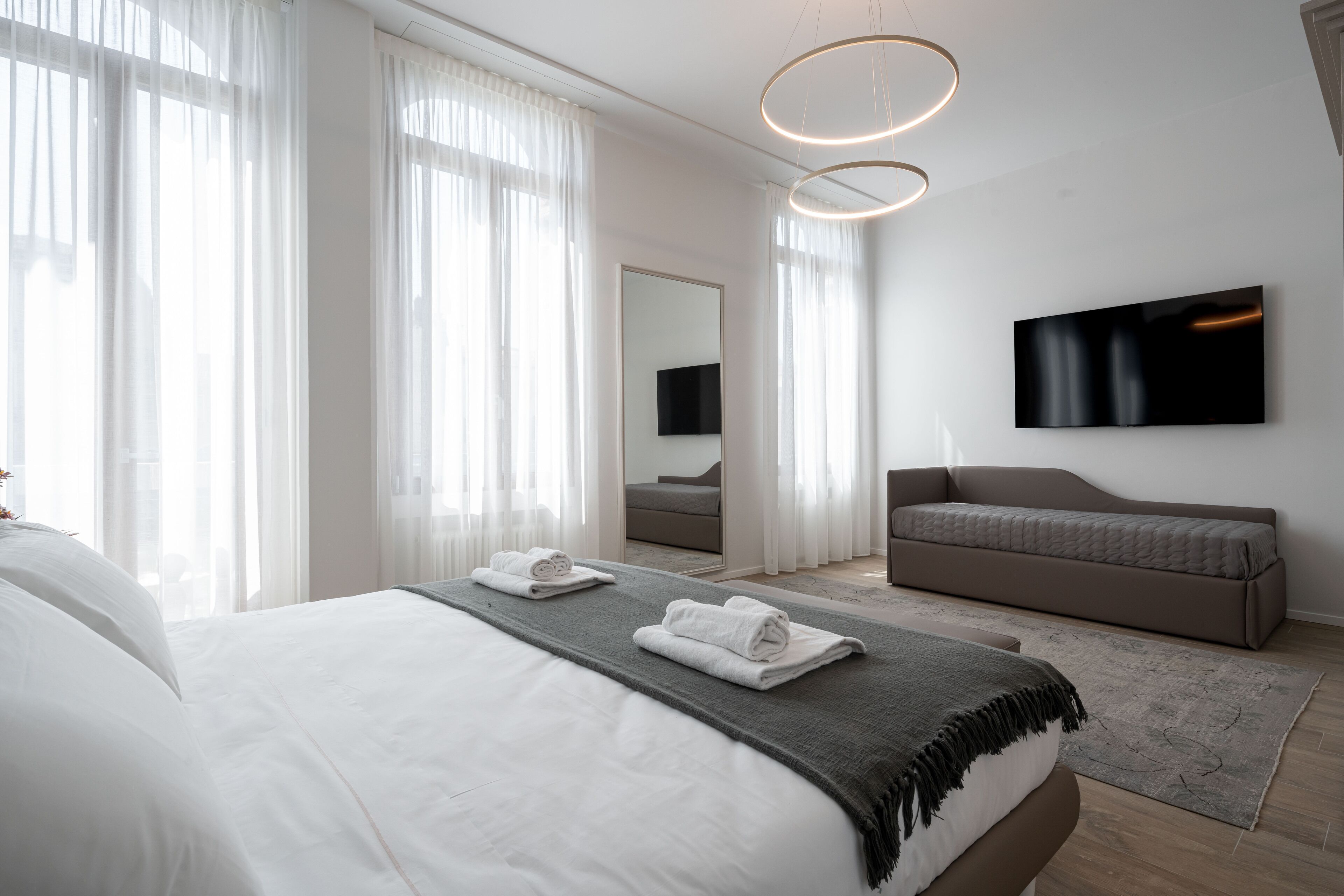 Een moderne hotelkamer met een groot bed, een bank, een flatscreentelevisie en een spiegel.