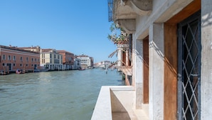 A canal with buildings on one side and a building with a balcony on the other. - Palace Canal View by Wonderful Italy (Venice)