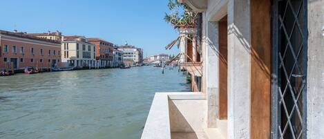 A canal with buildings on one side and a building with a balcony on the other.