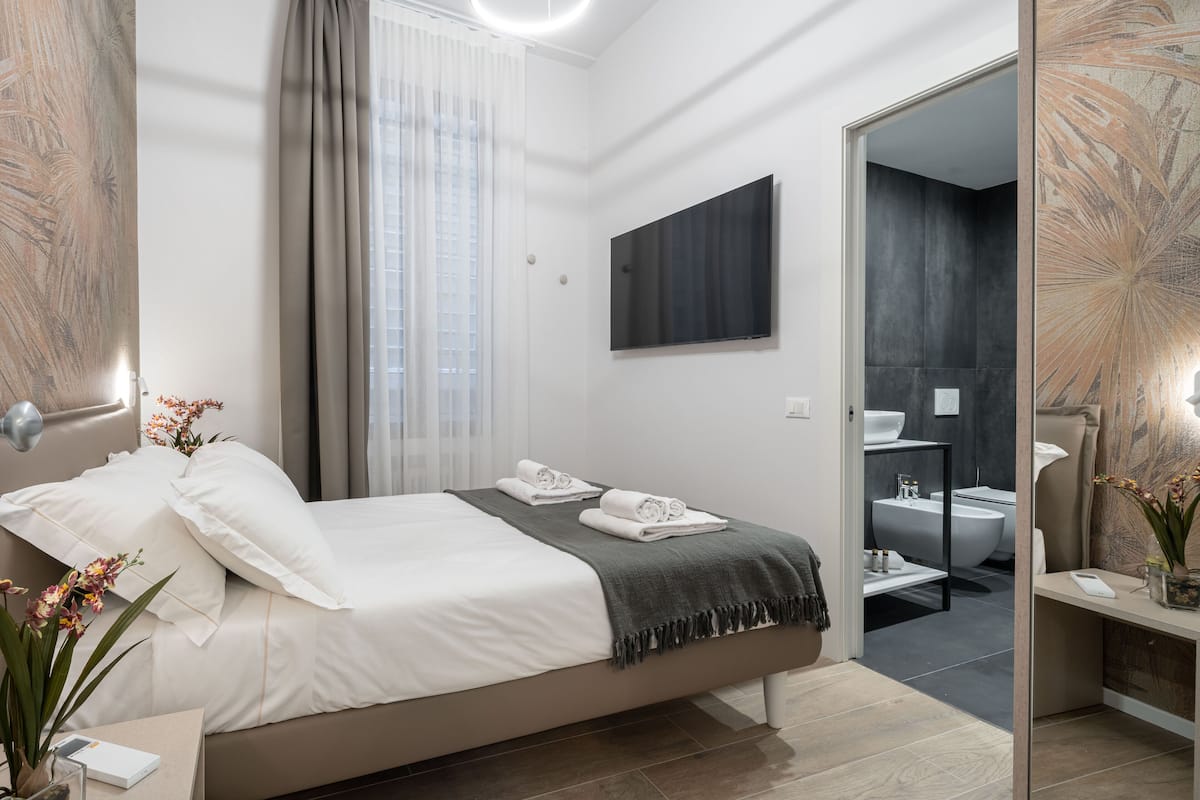 Une chambre moderne avec un grand lit, une table de chevet avec une lampe et une vue sur la salle de bain.