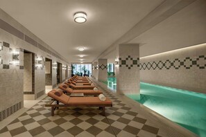A spa area with sun loungers, a pool, and tiled walls.