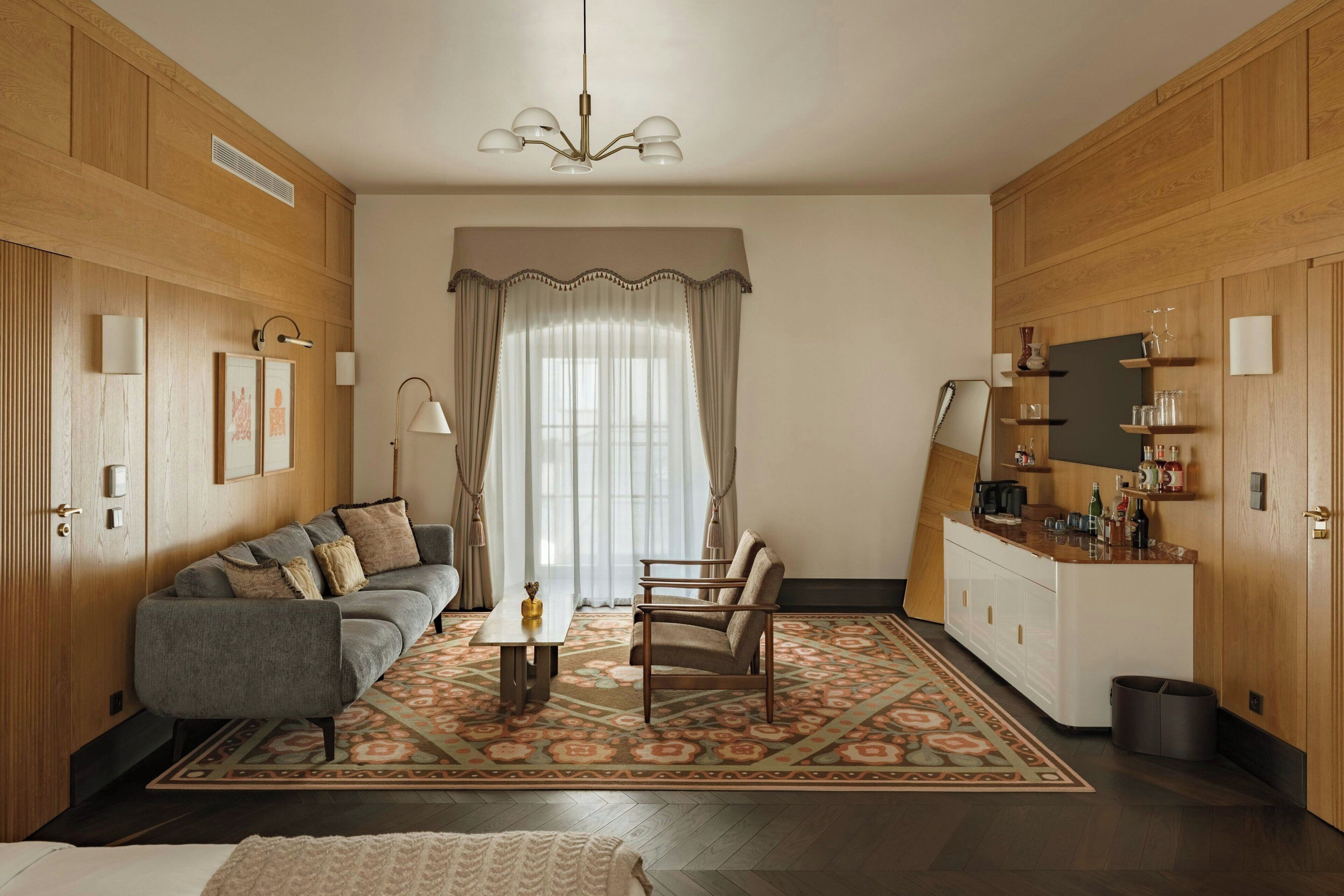 Ein Zimmer mit einer Couch, einem Sessel, einem Esstisch und einer Küchenzeile mit Schränken und einer Arbeitsfläche.