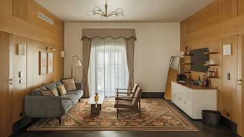 Een kamer met een slaapbank, fauteuil, eettafel en een keukenhoek met kastjes en een aanrecht.