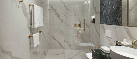 A modern bathroom with marble walls, a glass-enclosed shower, a black countertop, and a large mirror.