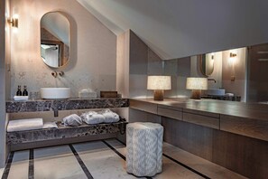 A modern bathroom with a marble countertop, a large mirror, and two wall-mounted lamps.