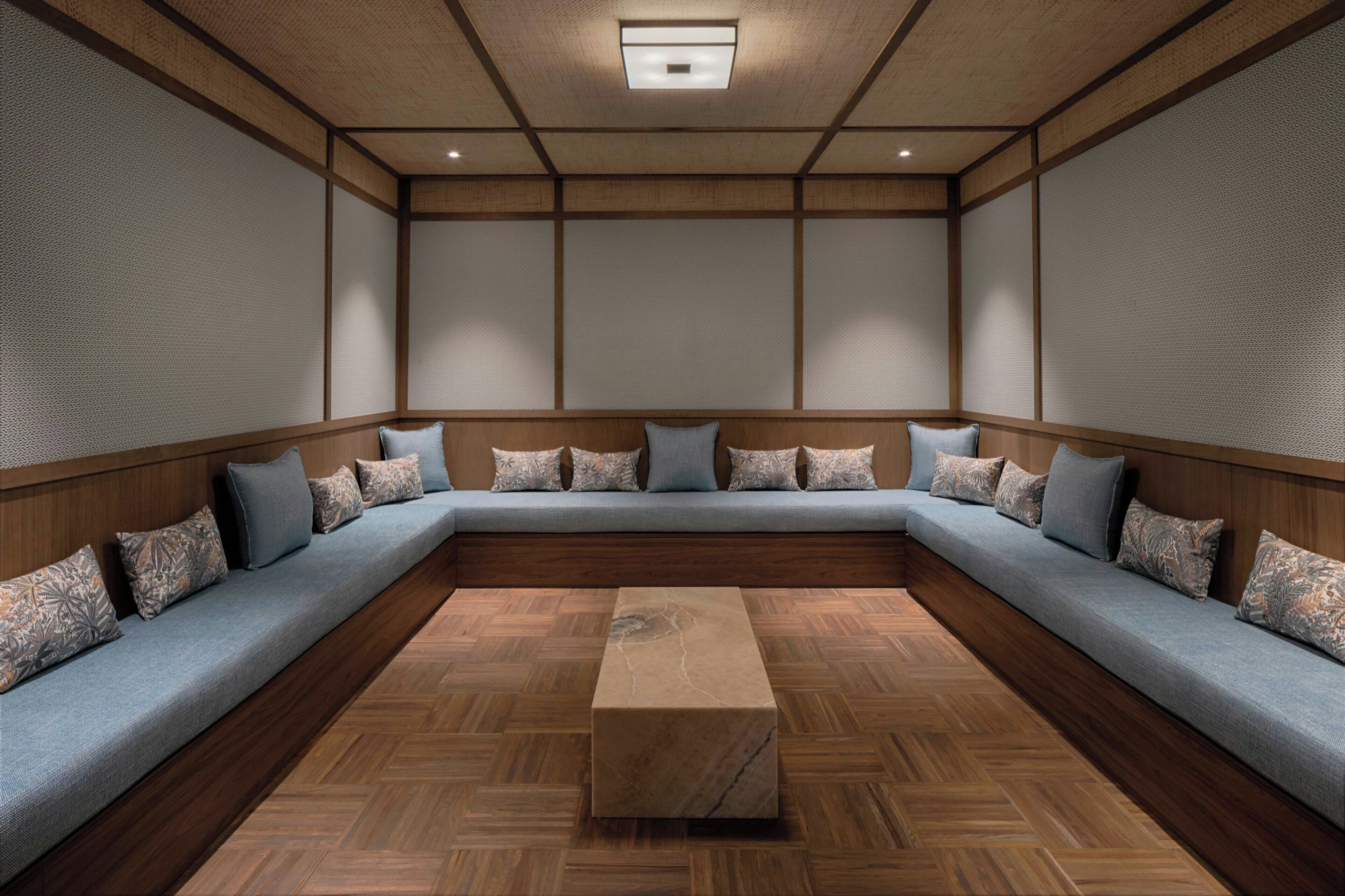 Una habitación con un amplio sofá modular en forma de L, una mesa de centro de madera y un suelo de madera con estampado de espiga.