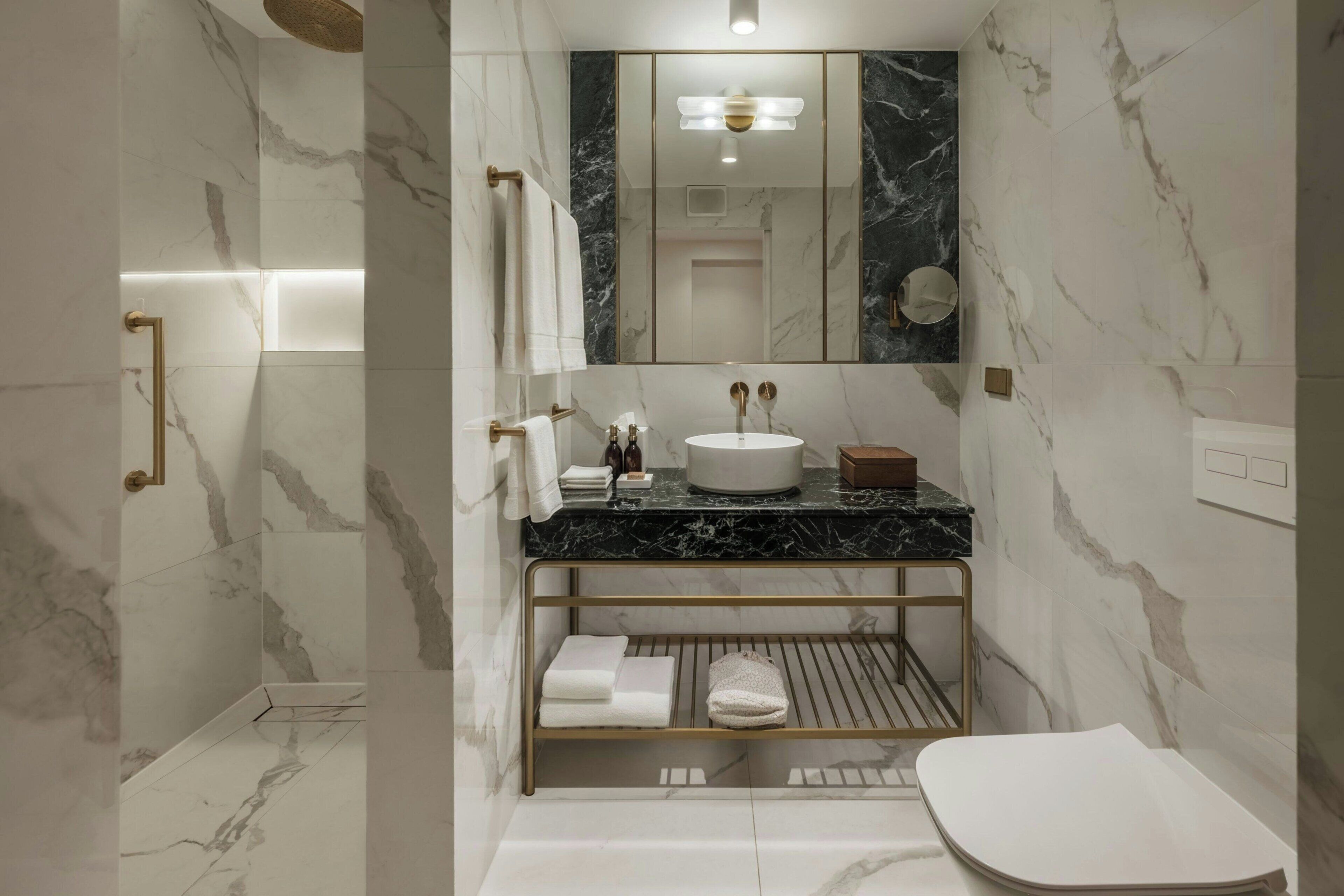 A modern bathroom with a marble vanity, a round sink, and a built-in shelf for towels.