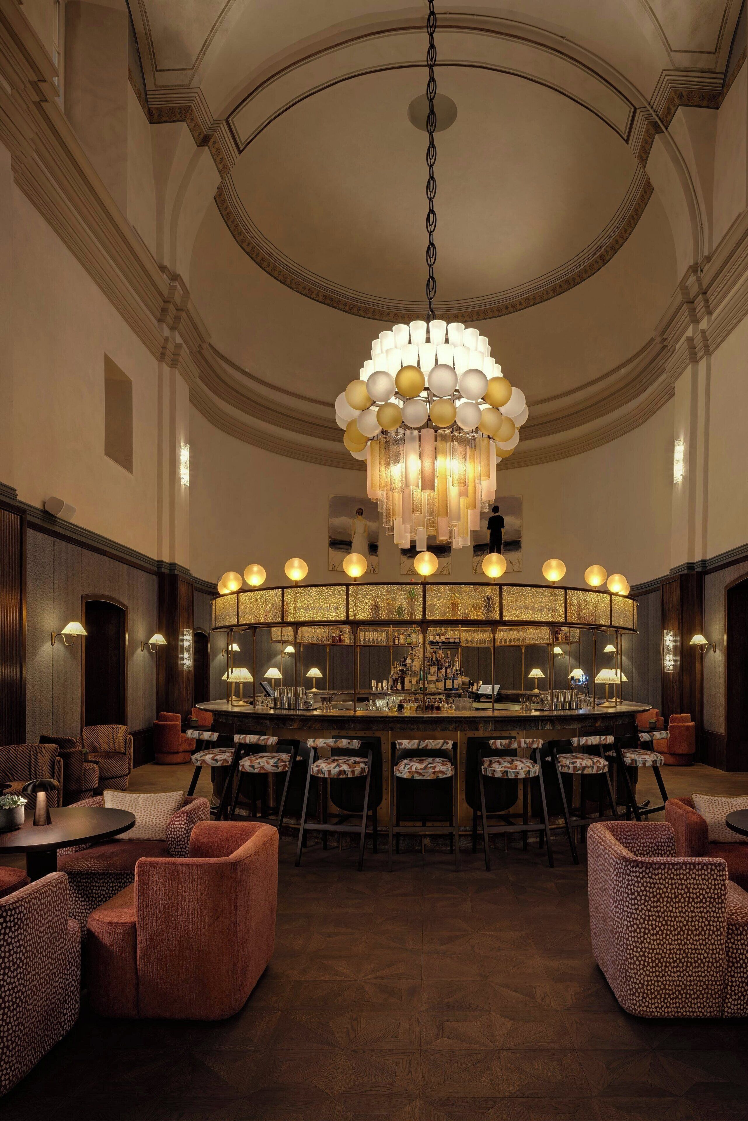 Zona de bar con candelabro, taburetes y mostrador con espejo.