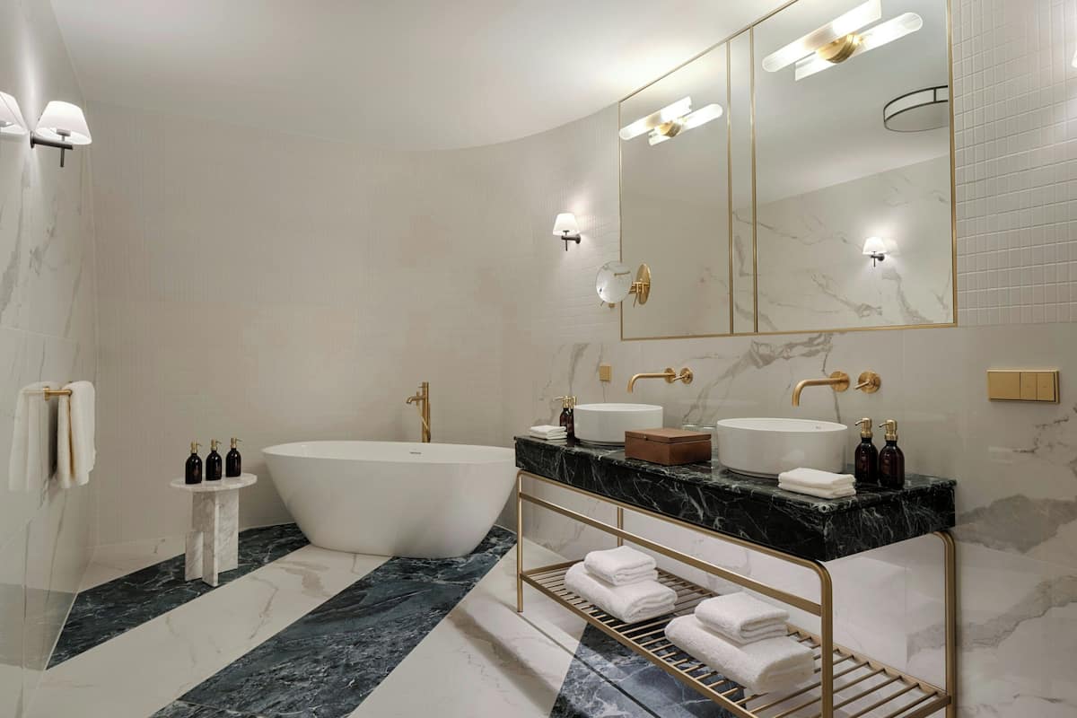 A modern bathroom with a freestanding bathtub, a vanity with a large mirror, and marble flooring.