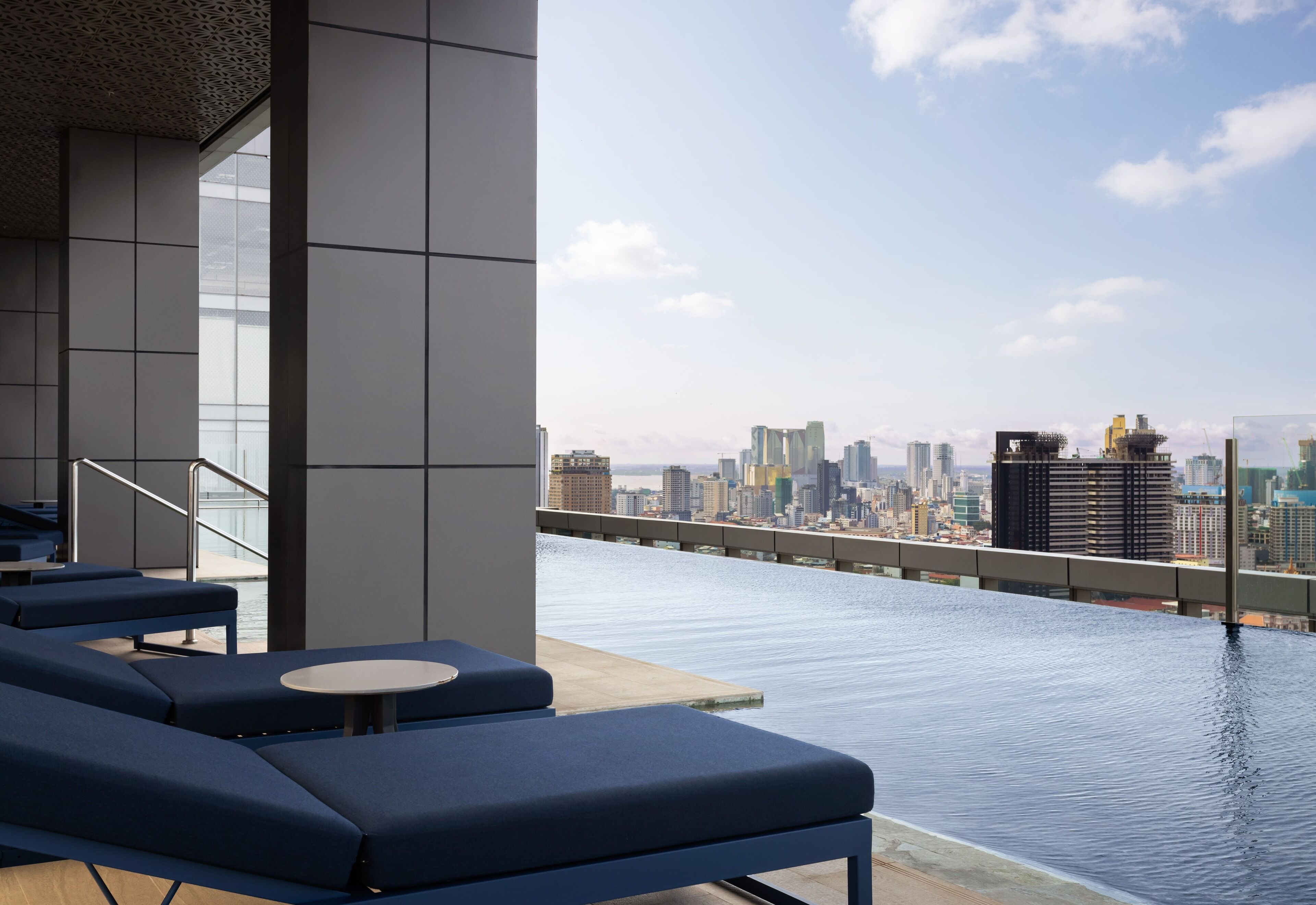 A rooftop pool area with lounge chairs and a city view.