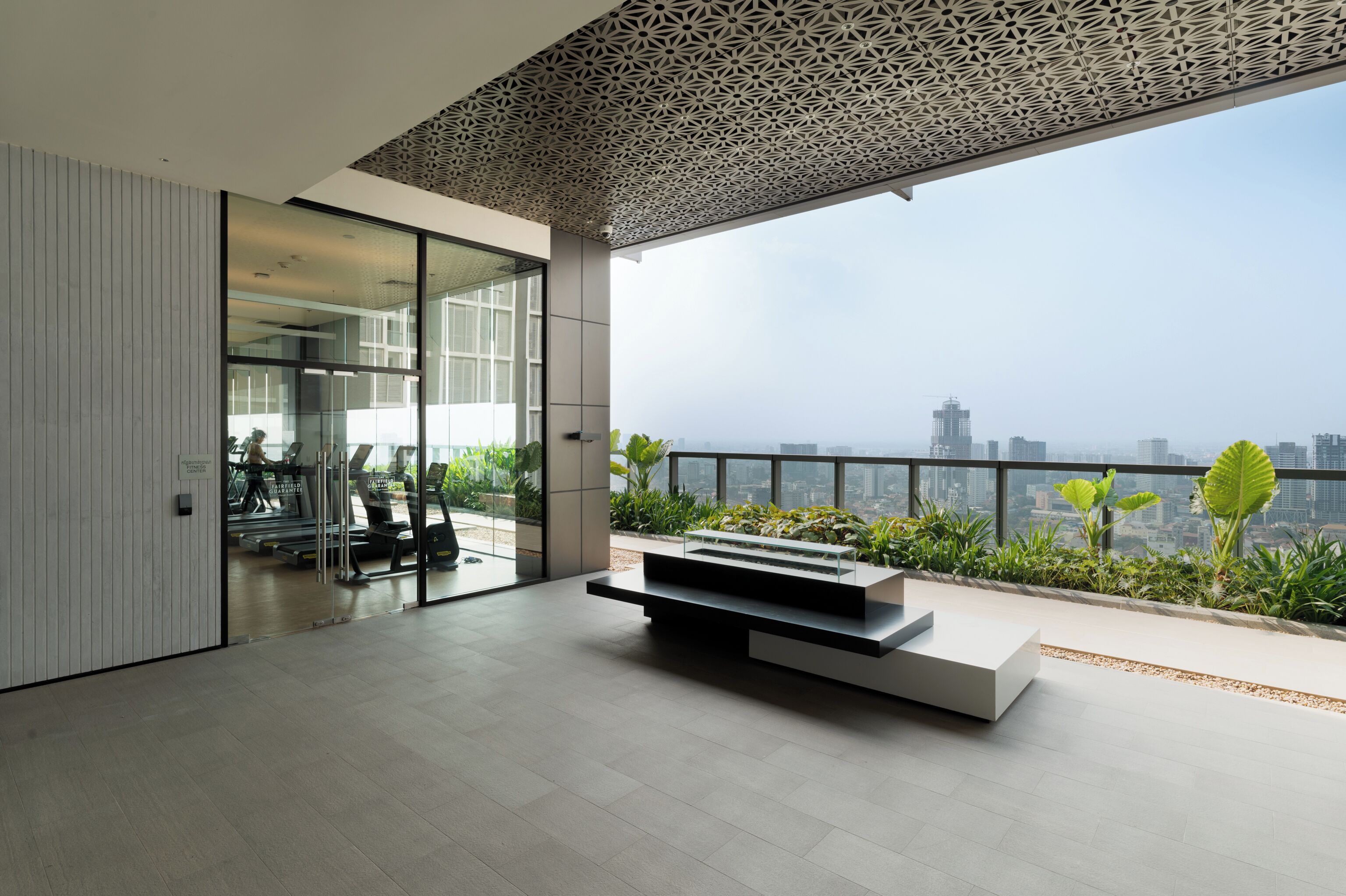 Un interior moderno con pared de vidrio, un banco minimalista y vista a la ciudad.