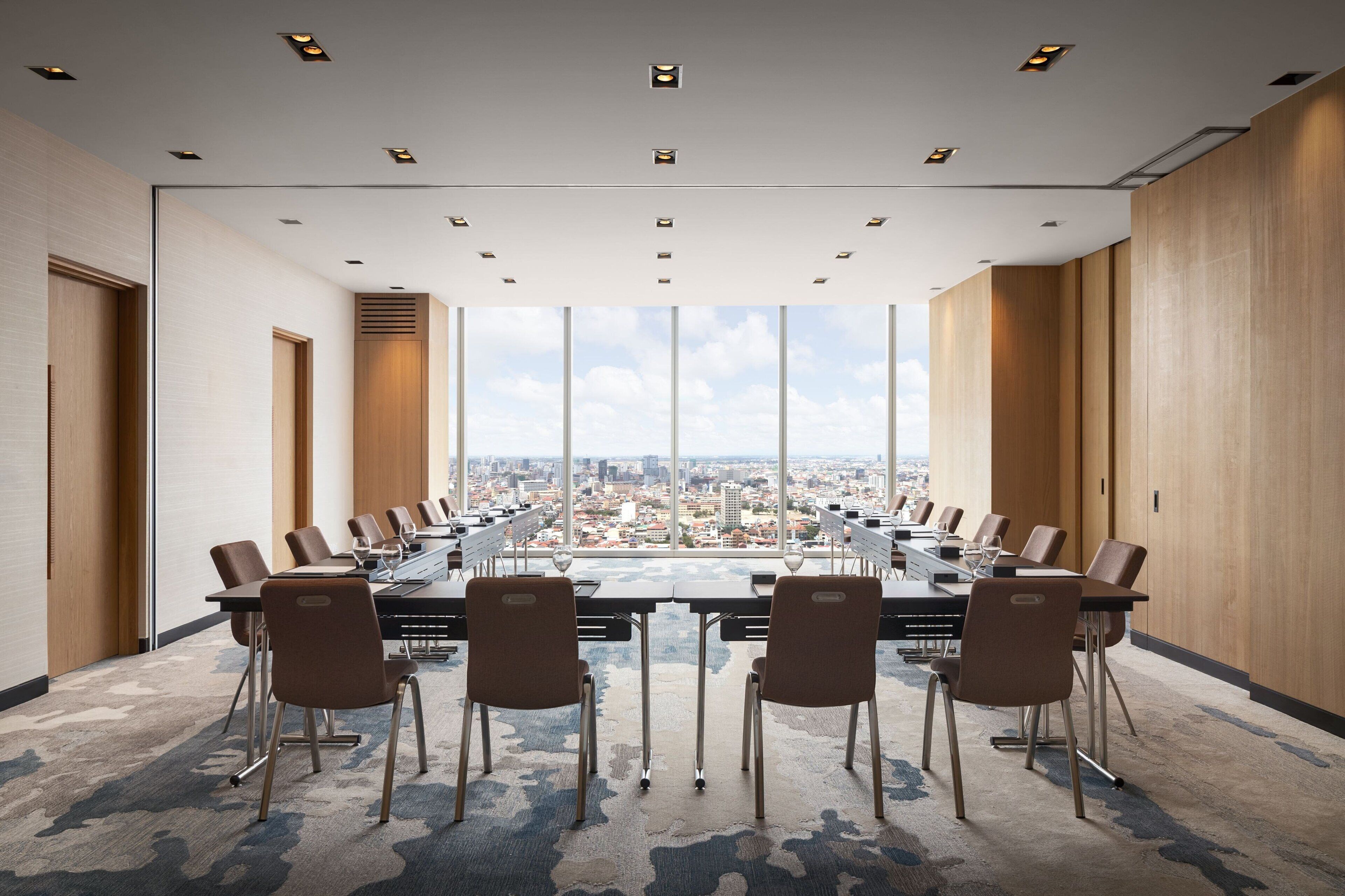 Une salle de conférence dotée d’une longue table, de nombreuses chaises et offrant une vue sur la ville grâce à de grandes fenêtres.