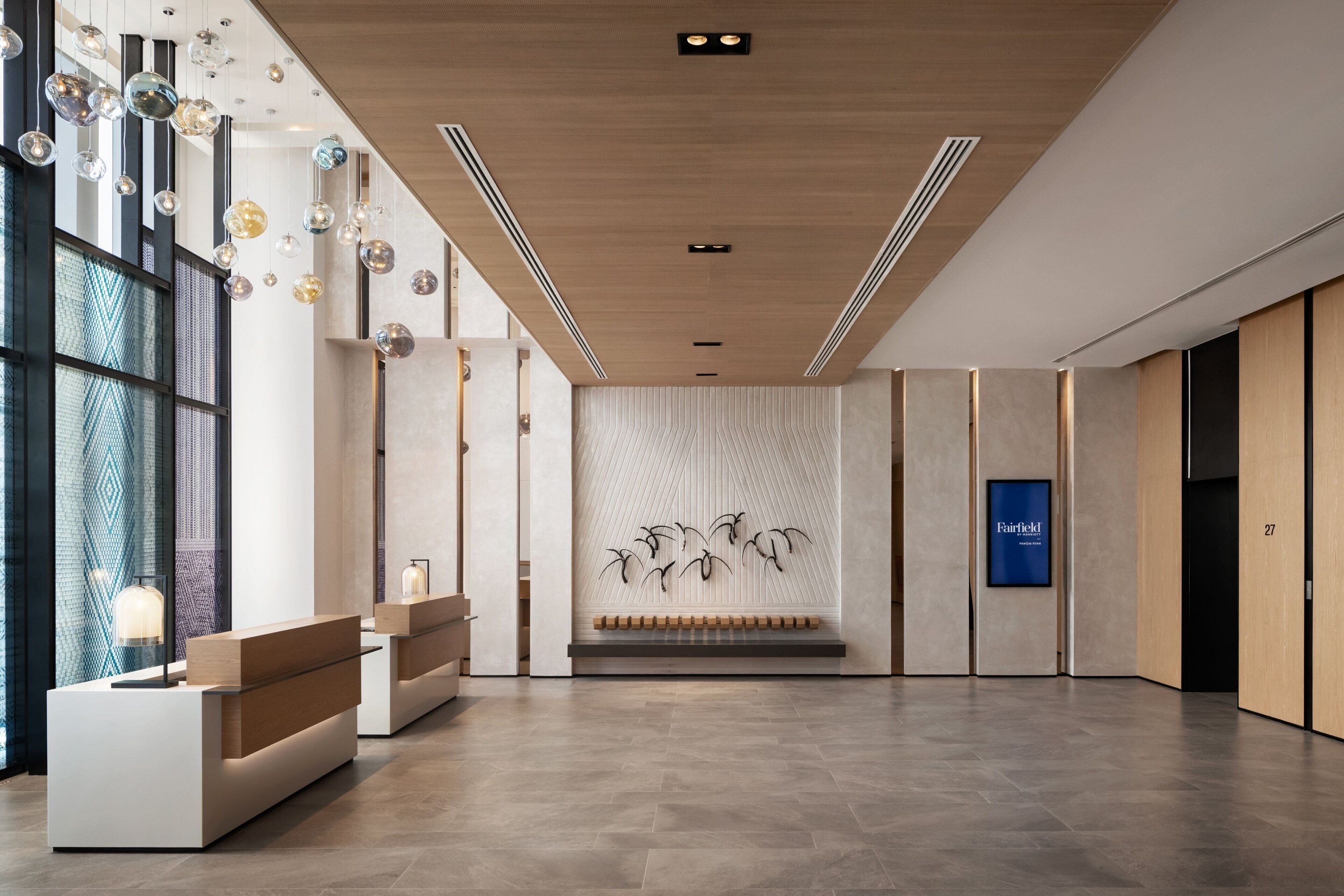 Un espace d’accueil moderne avec un plafond en bois, un coin salon et une œuvre d’art fixée au mur.