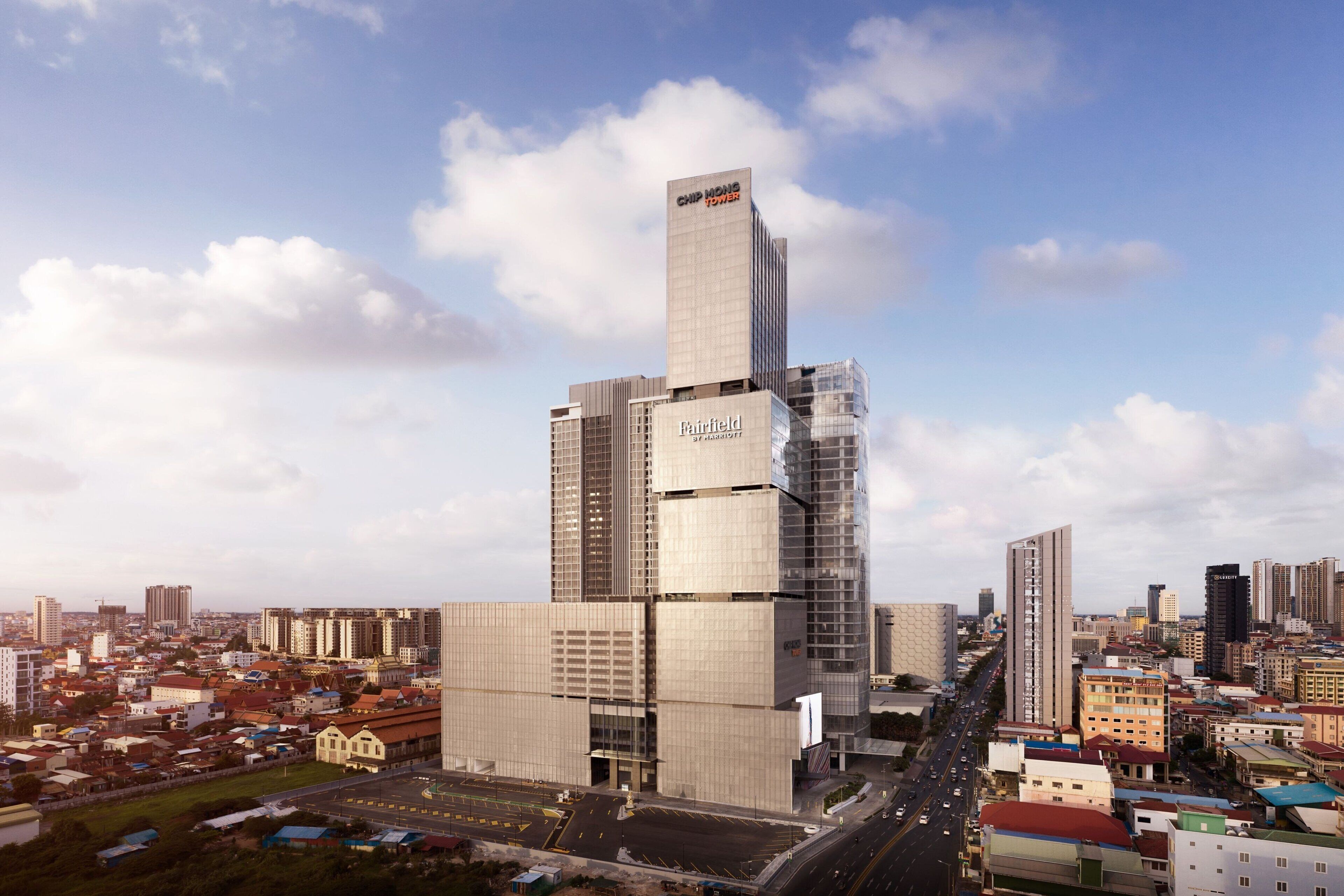 A modern high-rise building with a prominent 'Chipmond Tower' sign, surrounded by a dense urban area with various other buildings.