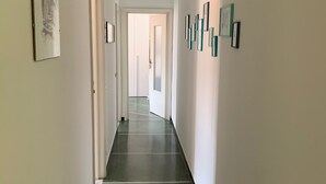 A hallway with a green carpet, white walls, and framed pictures on the walls. - CRÊUZA DE MÄ - nice apartment with convenient parking space by the sea (Rapallo)