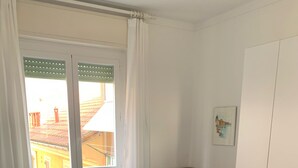 A bedroom with a bed, a dresser, a radiator, and a window with curtains. - CRÊUZA DE MÄ - nice apartment with convenient parking space by the sea (Rapallo)