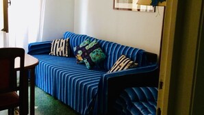 A small, cozy room with a blue-striped sofa, a wooden chair, and a framed picture on the wall. - CRÊUZA DE MÄ - nice apartment with convenient parking space by the sea (Rapallo)