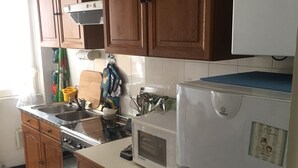 A kitchen with wooden cabinets, a stainless steel sink, a microwave, and a white refrigerator. - CRÊUZA DE MÄ - nice apartment with convenient parking space by the sea (Rapallo)
