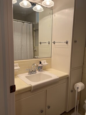 Un baño con lavamanos blanco, un espejo y cortina de ducha.