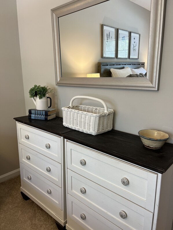 A white dresser with drawers, a mirror above it, and a small white basket on top. - 2.0 to the Masters! (Augusta)