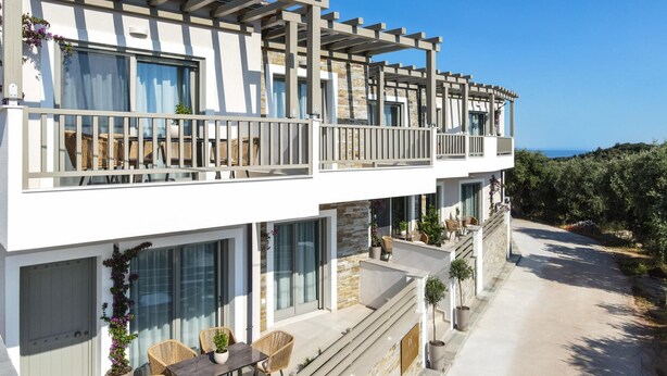 A modern two-story building with a balcony, outdoor seating, and a view of the sea. - Premium Apartment (Thasos)