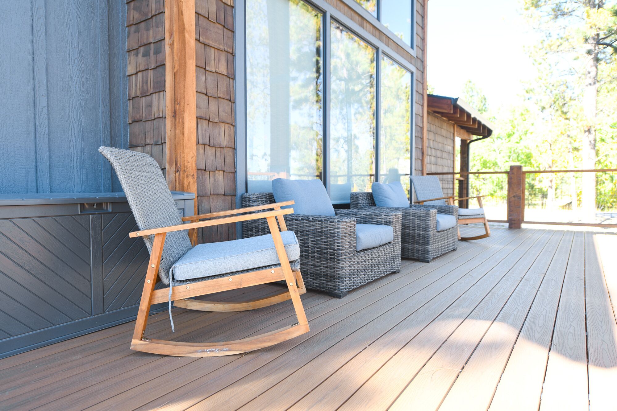 A wooden deck with wicker furniture and a rocking chair.