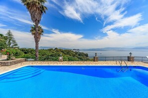 A swimming pool with a view of a body of water and distant mountains.