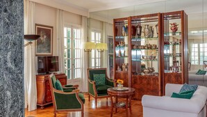 Un vaste salon doté d’une cheminée en marbre, d’un téléviseur, d’un fauteuil vert, d’un canap é blanc et d’un meuble en bois orné d’objets décoratifs.