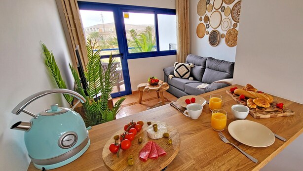 Un coin repas avec une table mise pour le petit-déjeuner, comprenant des tomates, des olives et du pain.
