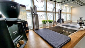 Une cuisine équipée d’une machine à café, d’un évier et de divers ustensiles.