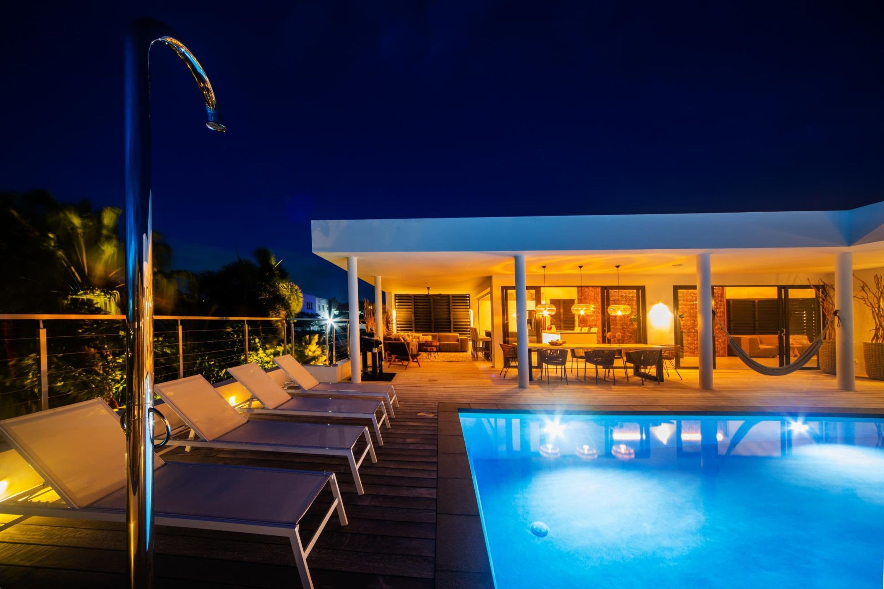 Un área de piscina moderna al aire libre con sillones de descanso y comedor.