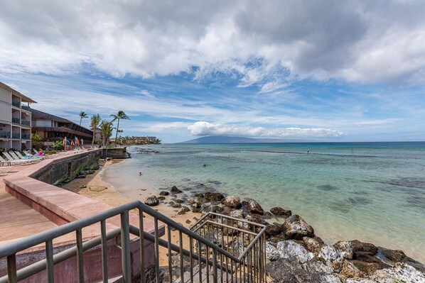 A beachfront hotel with a pool, a staircase leading to the beach, and a view of the ocean.