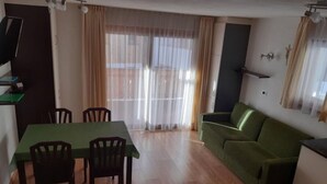 A room with a dining table, chairs, a sofa, and a TV. - Apartment Raisc - your home in Val Badia (La Villa)