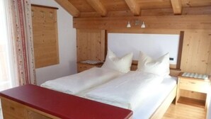 A wooden bedroom with a bed, a desk, and a dresser. - Apartment Raisc - your home in Val Badia (La Villa)