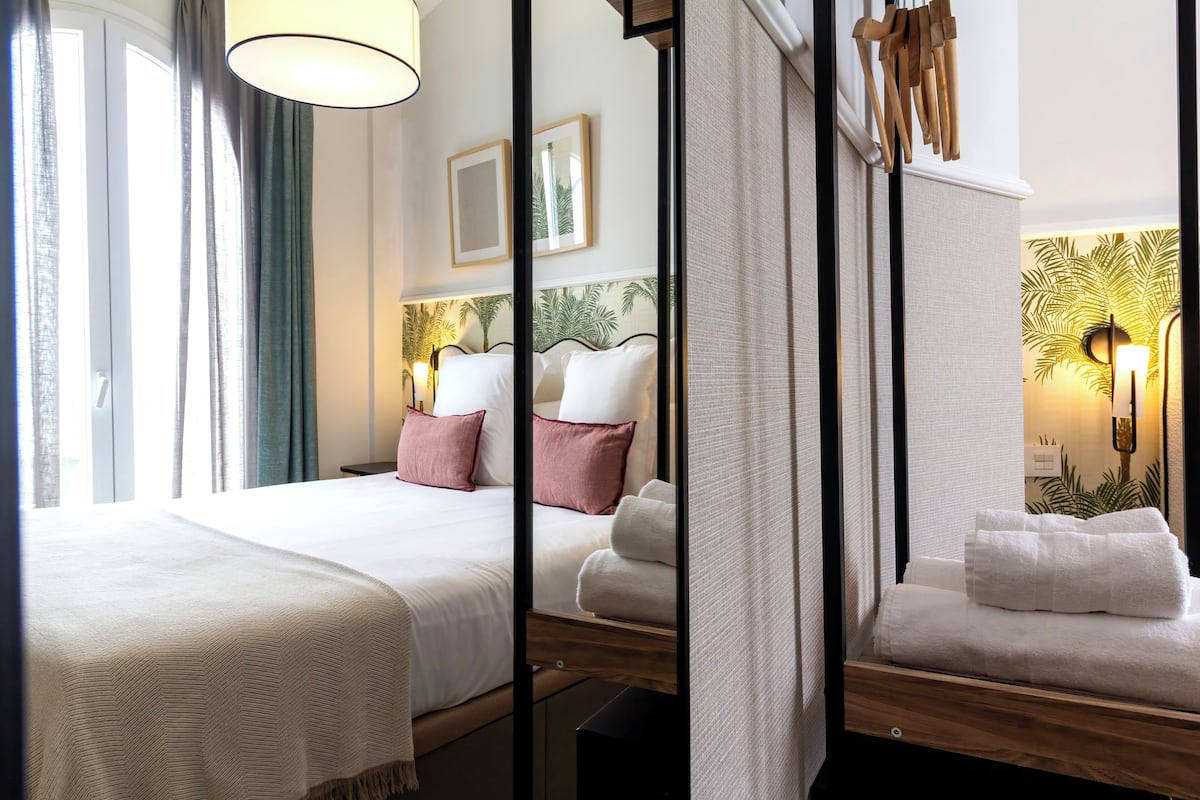 Ein Hotelzimmer mit einem großen Bett, einem Nachttisch, einem Spiegel und einer Wandlampe.