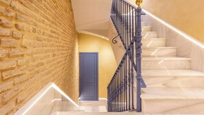 Una scala con gradini in marmo e ringhiera in metallo nero, che conduce a una porta con cornice blu.
